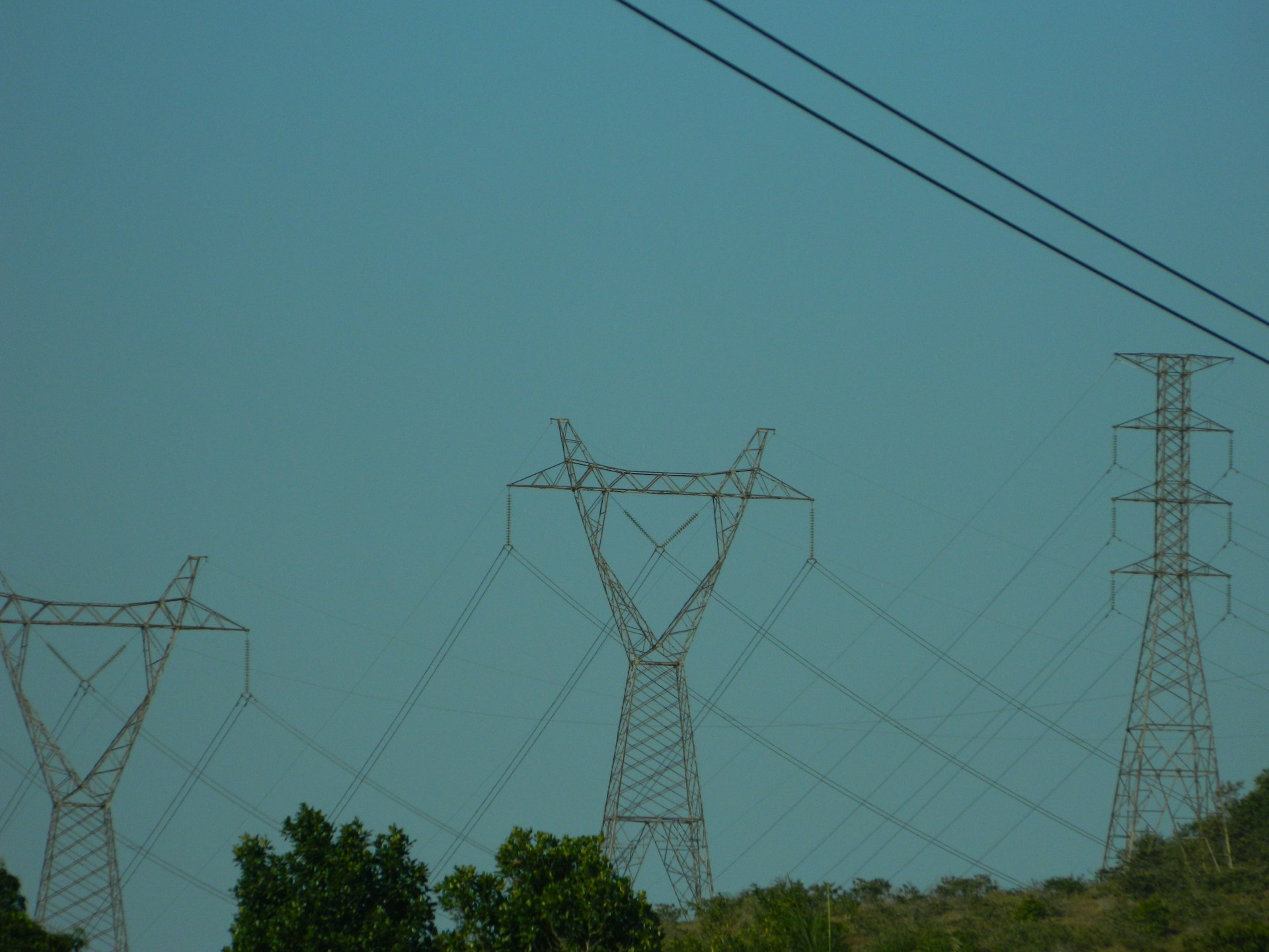 A plane flying in the sky over power lines